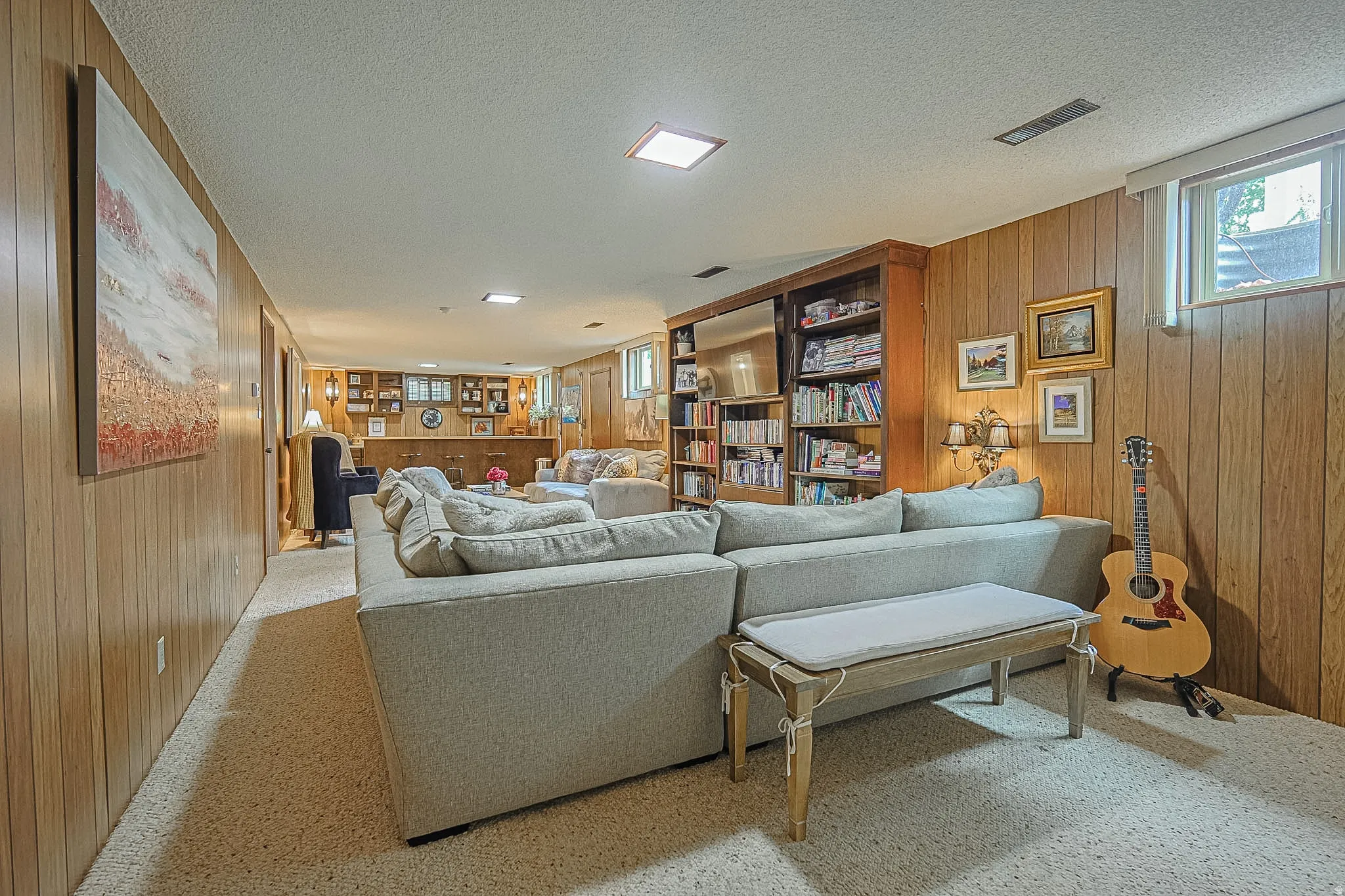 Carpeted living area featuring wood-paneled walls and a built-in wooden bookcase