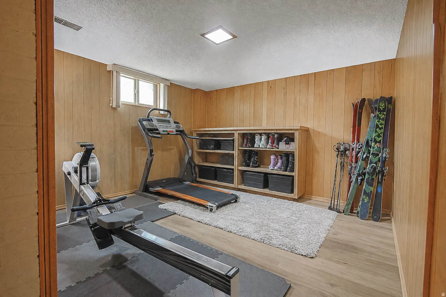 Wood-paneled room featuring a window, built-in shelving, recessed ceiling lighting, and wood-finish flooring