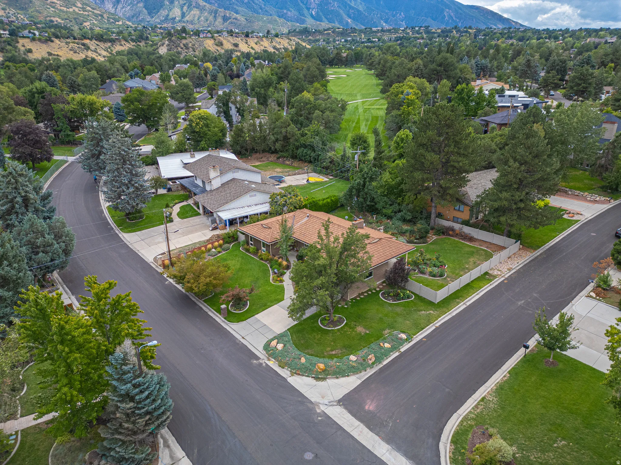 Property with a tile roof and green landscaping, situated on a curved street with mountain backdrop