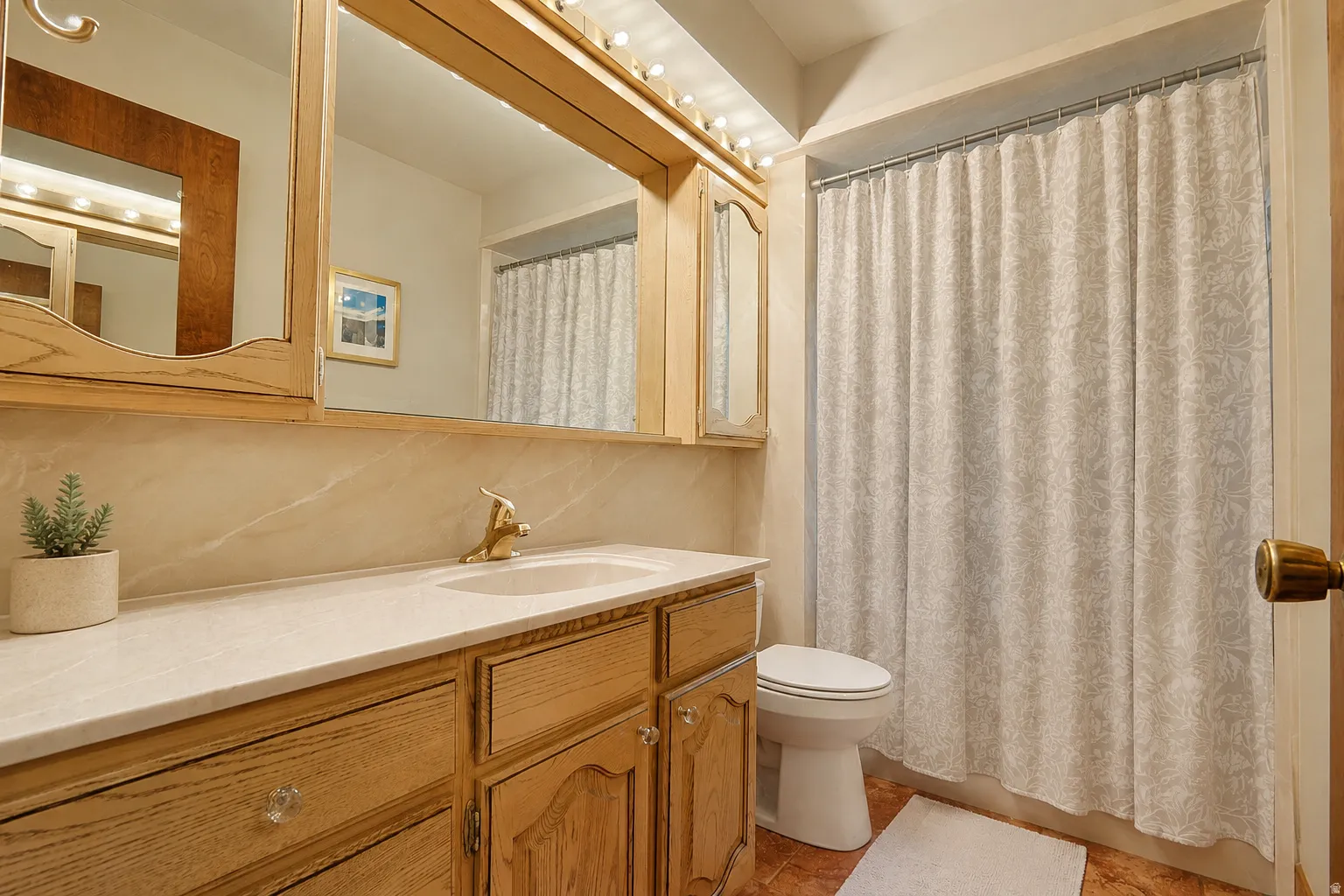 Vanity with wood-finish cabinetry, integrated sink, and light-colored countertop