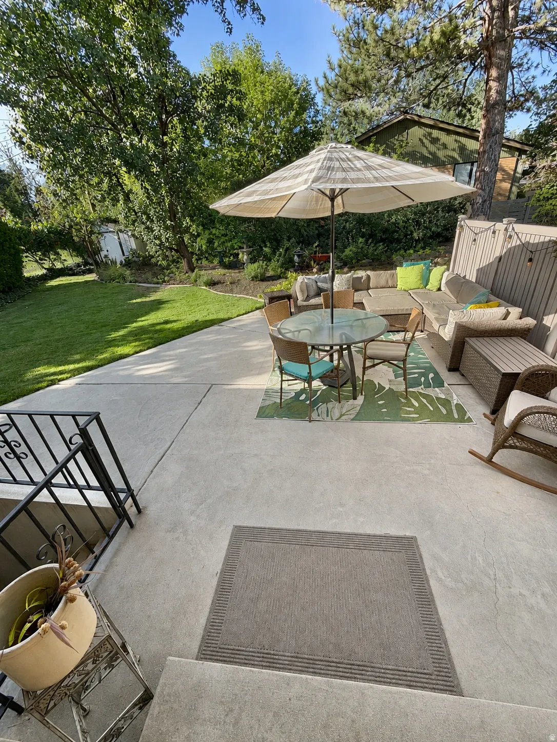 Expansive concrete patio with integrated steps, featuring an ornate metal railing