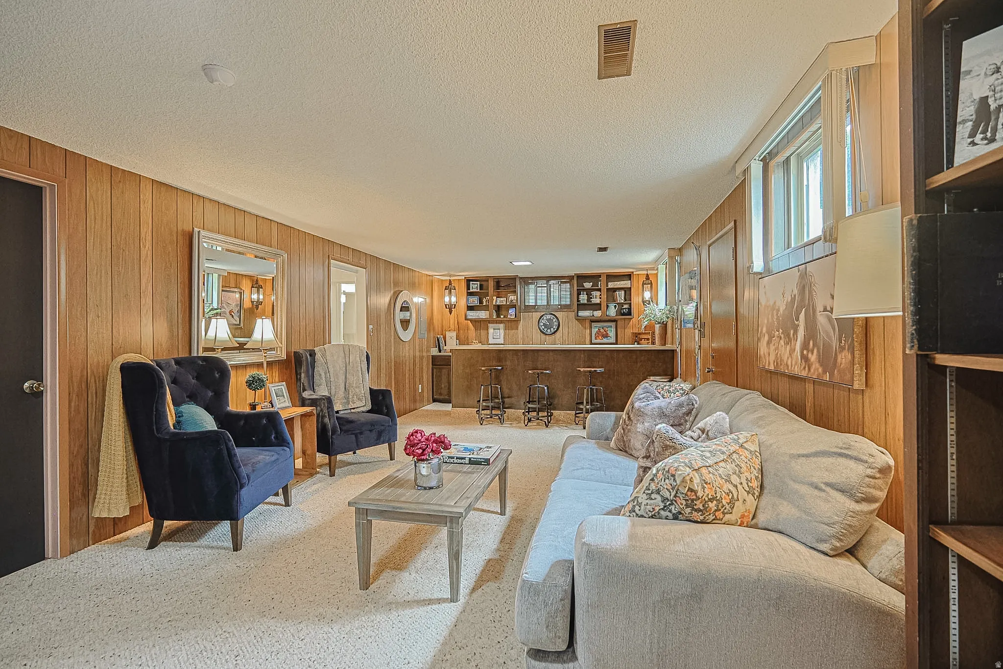 Recreation room featuring wood-paneled walls, built-in shelving, a wet bar, and carpet flooring
