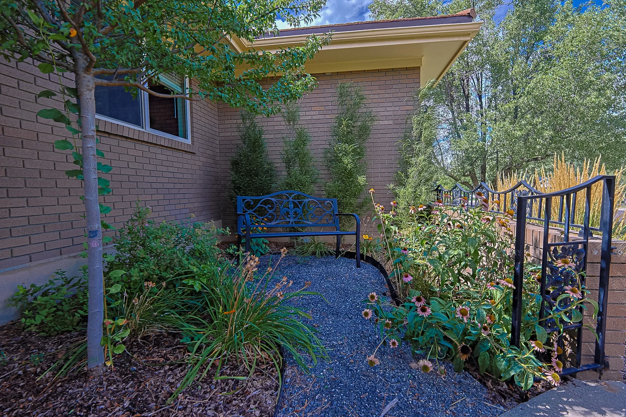 Brick exterior with a gravel pathway and mature landscaping