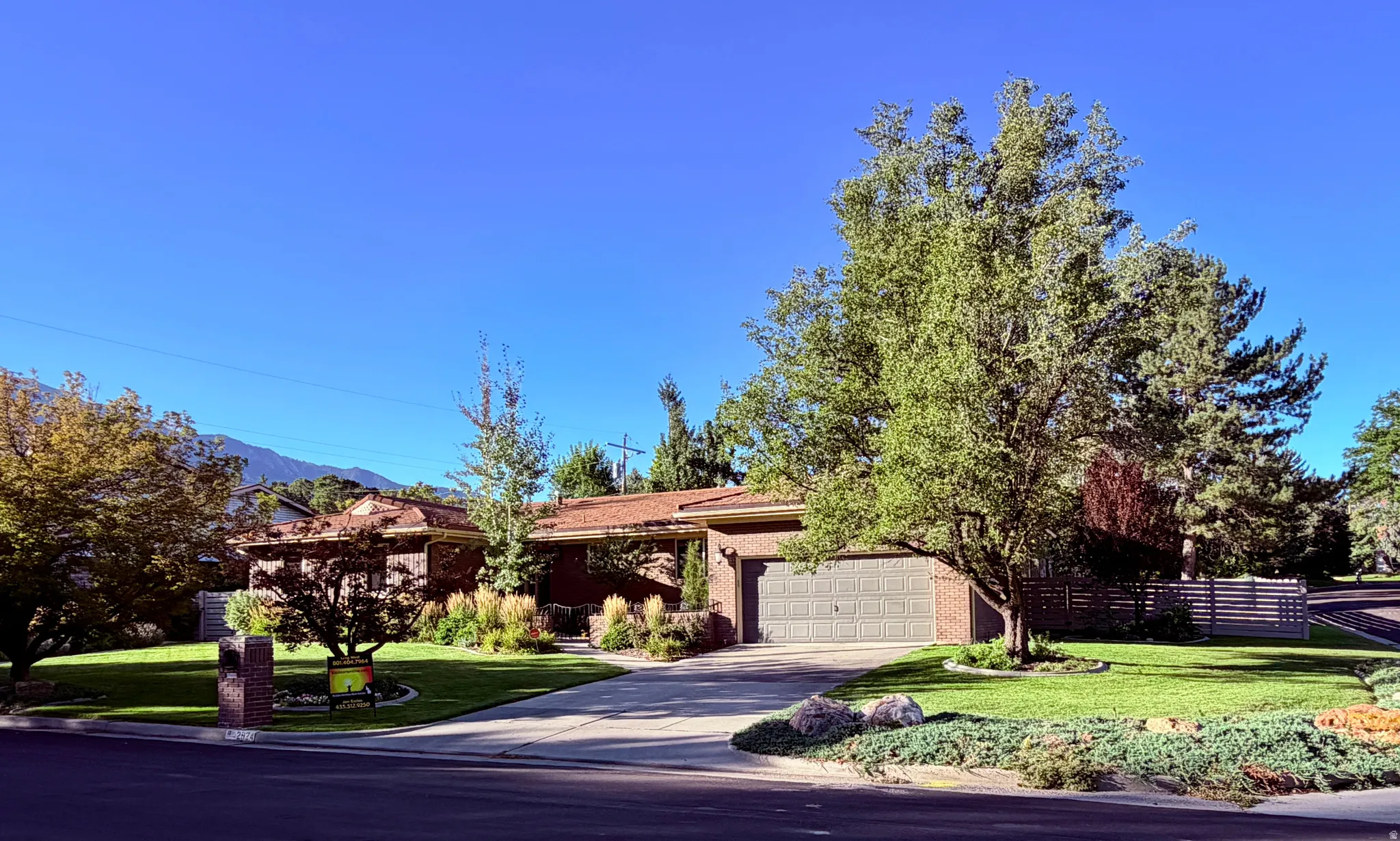 Brick exterior with a two-car garage, mature landscaping, and a substantial driveway