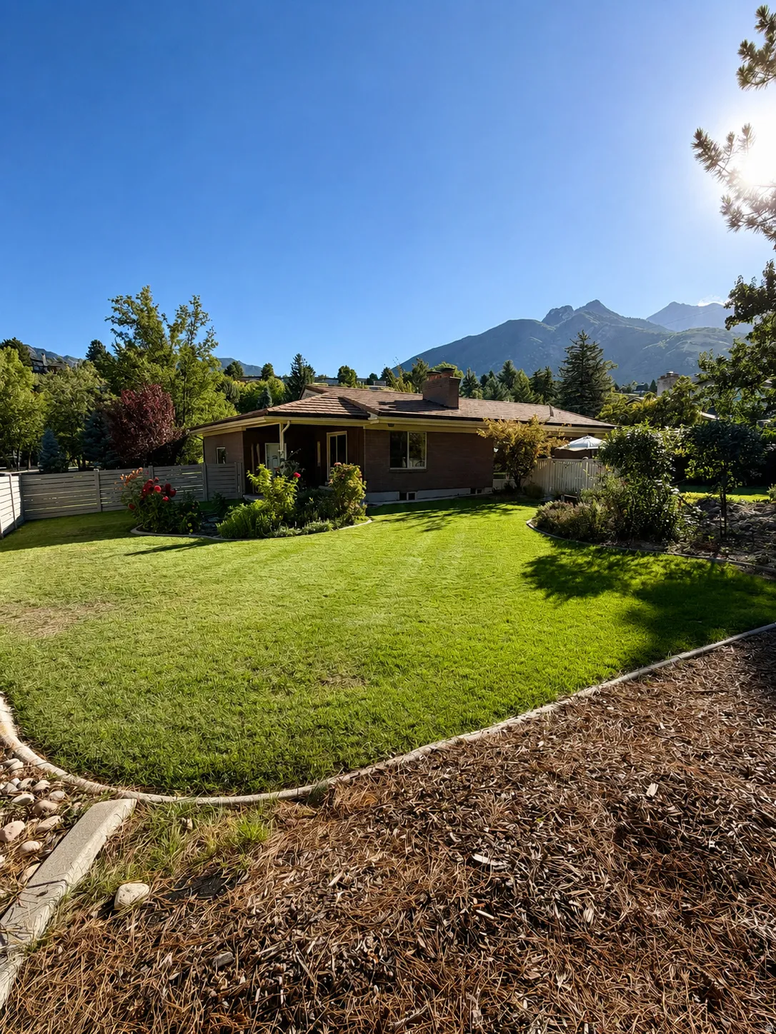 Expansive lawn with defined landscaping borders and mature trees