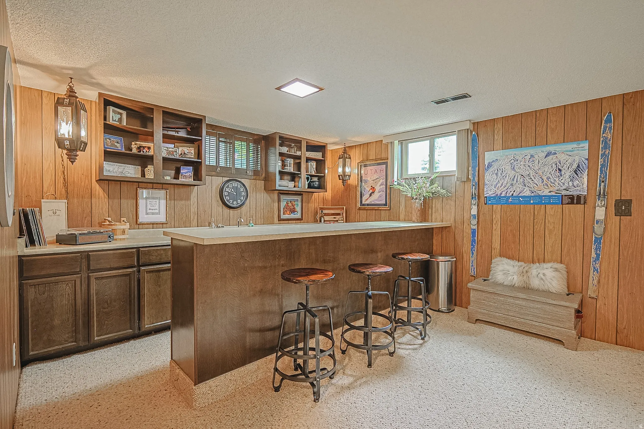 Built-in wet bar with a light-toned countertop, wood-paneled walls, built-in open shelving, and recessed lighting