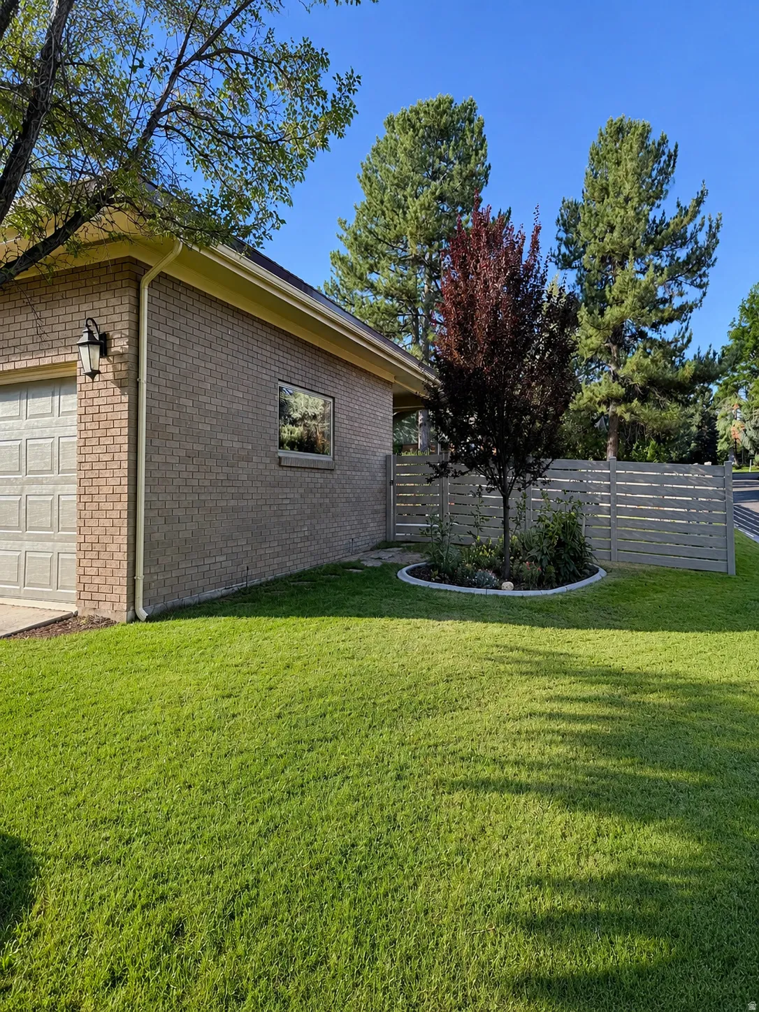 Brick exterior with an attached garage, featuring a well-maintained lawn and a privacy fence