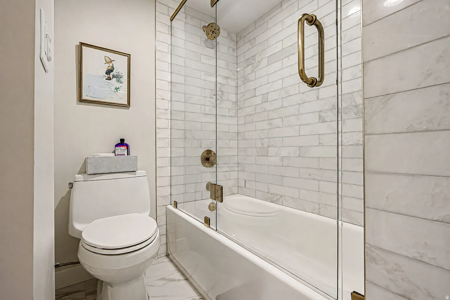 Subway tile shower surround with a fixed glass panel enclosure and brass hardware