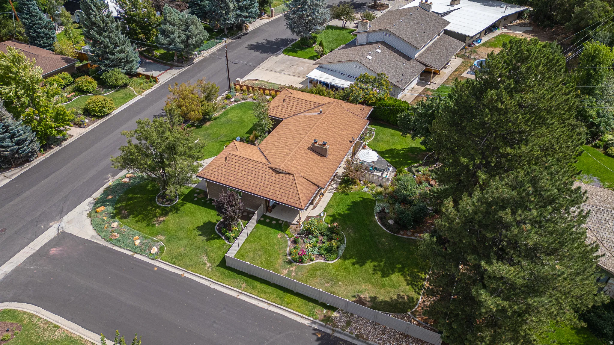 Expansive lot featuring a mature tree, manicured lawn, and paved roadways
