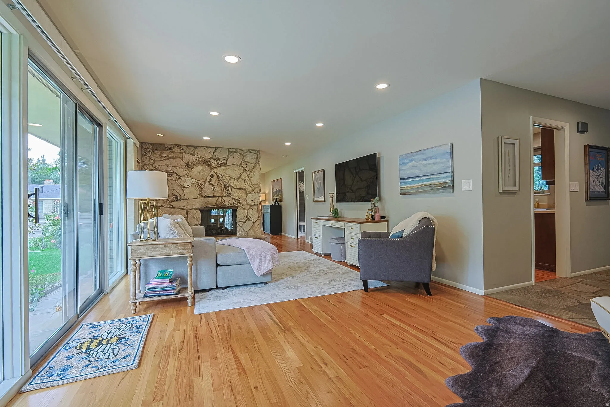 Hardwood flooring, recessed lighting, and a stone-clad fireplace