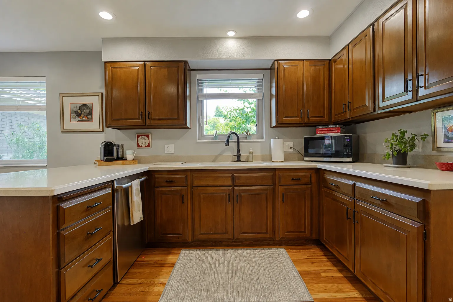 Wood-finish cabinetry, light-toned countertops, stainless steel sink, black gooseneck faucet, and recessed lighting