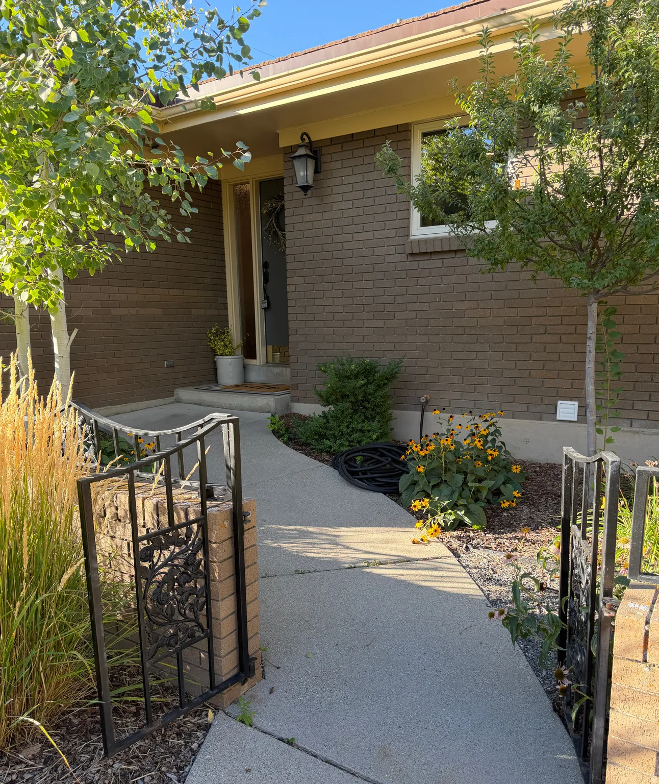 Brick exterior featuring a covered entry, exterior lighting, and a concrete pathway