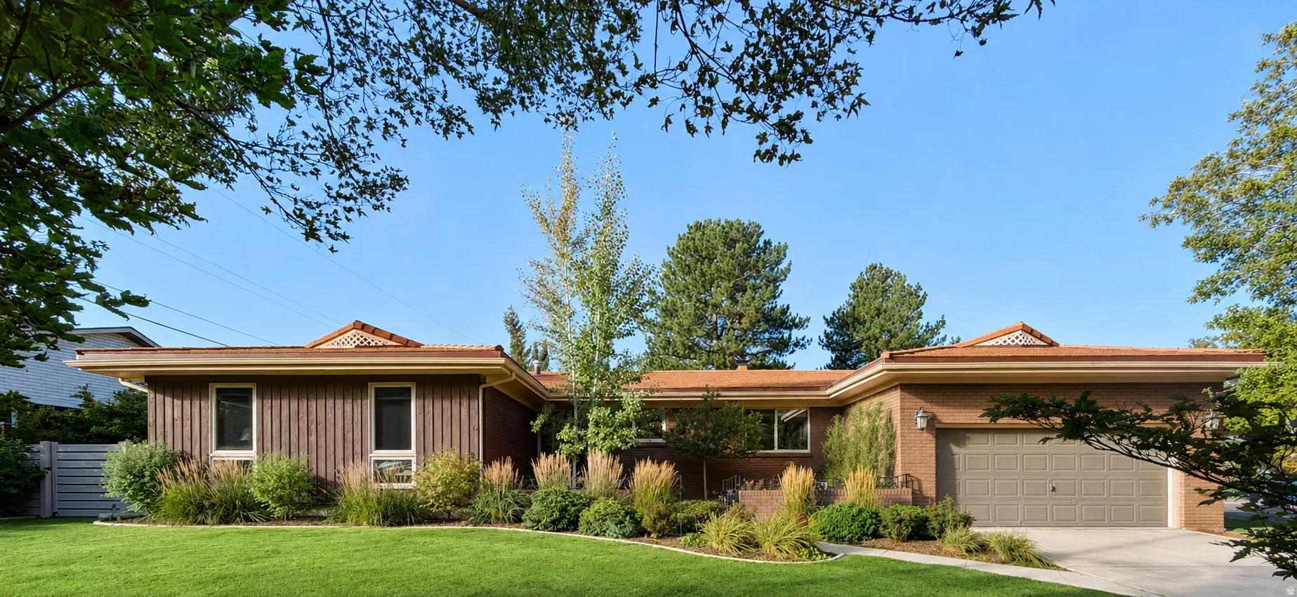 Front exterior with a brick and vertical wood siding facade, a two-car garage, and a lush lawn