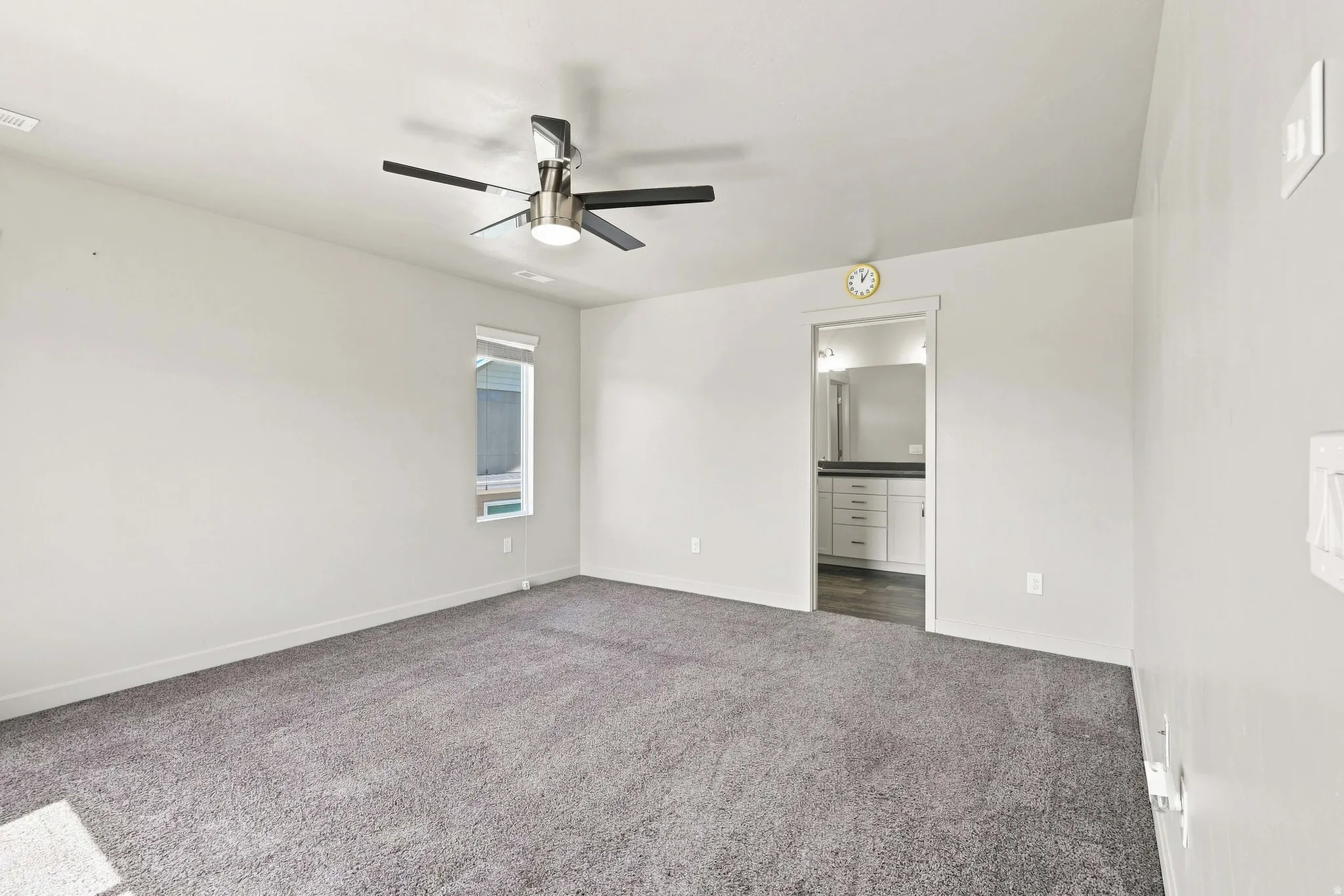 Spacious room featuring neutral carpeting, a ceiling fan with integrated lighting, and a single window with blinds