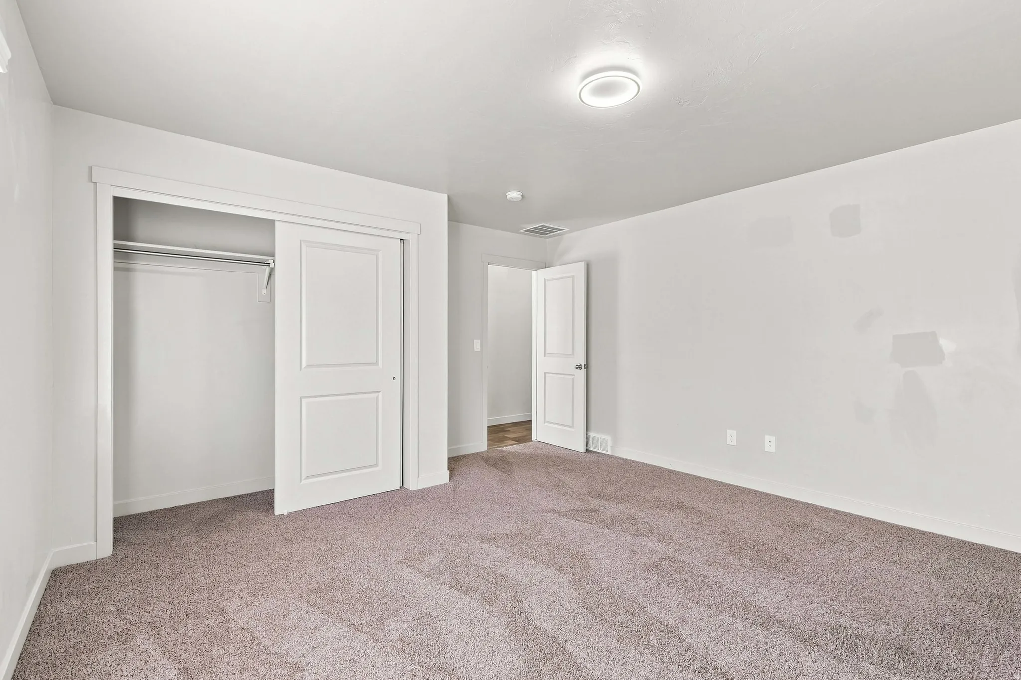 Plush carpet flooring, white walls, white trim, recessed lighting, and a bi-fold closet with two-panel doors