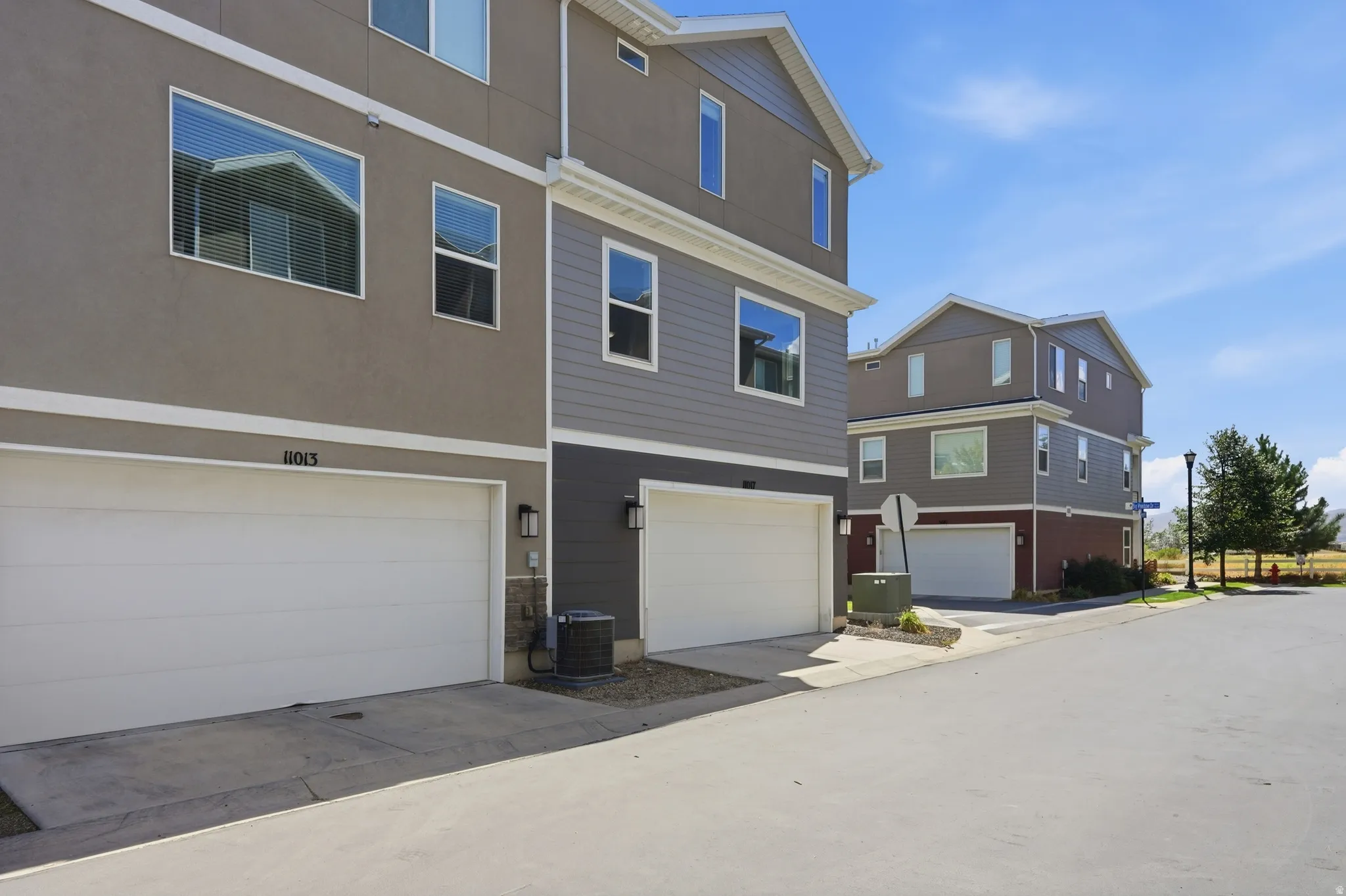 Contemporary townhome architecture featuring a two-car garage, stucco and siding exterior, and multiple windows