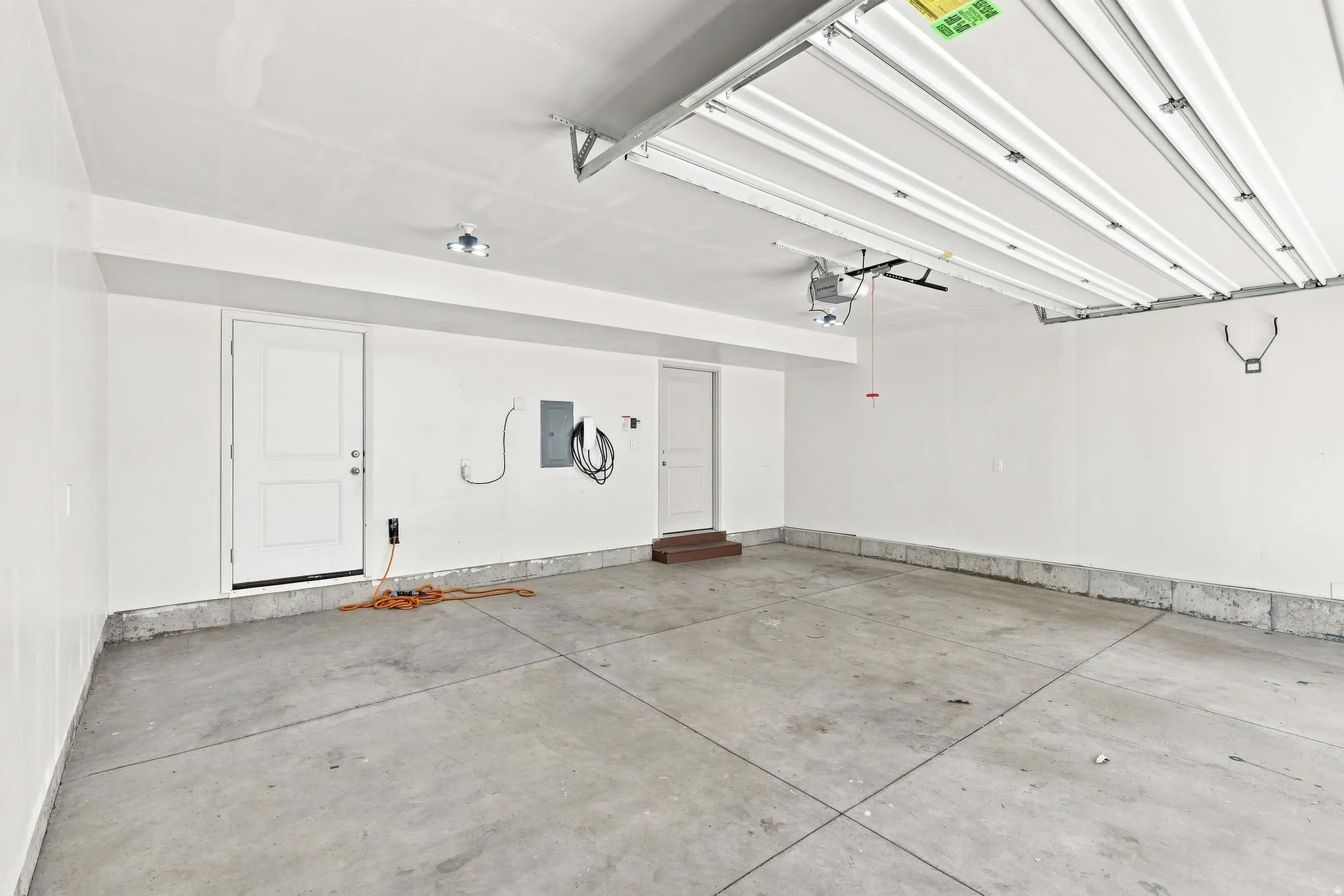 Spacious garage with concrete flooring, overhead lighting, and white walls