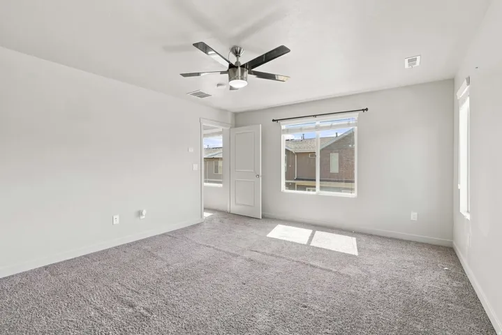 Spacious interior with neutral-toned walls, gray carpeting, and a contemporary ceiling fan