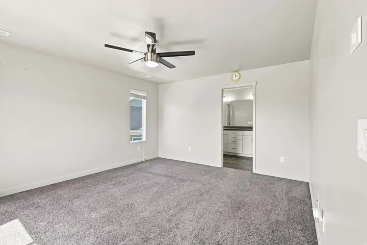 Spacious room featuring neutral carpeting, a ceiling fan with integrated lighting, and a single window with blinds