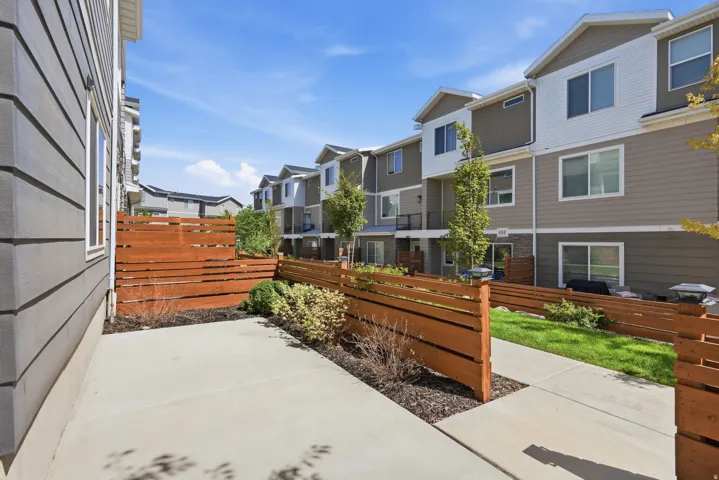 Private patio area with concrete paving and wood fencing, surrounded by landscaping