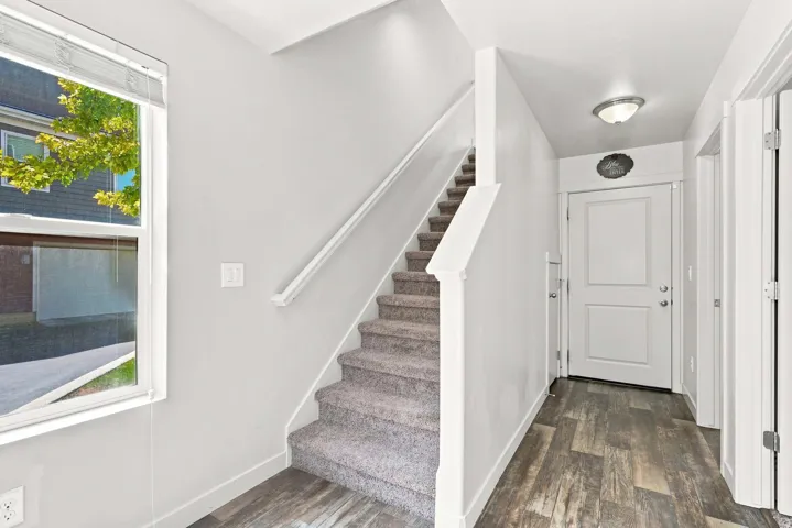 Wood-finish flooring leading to a carpeted staircase with a white handrail
