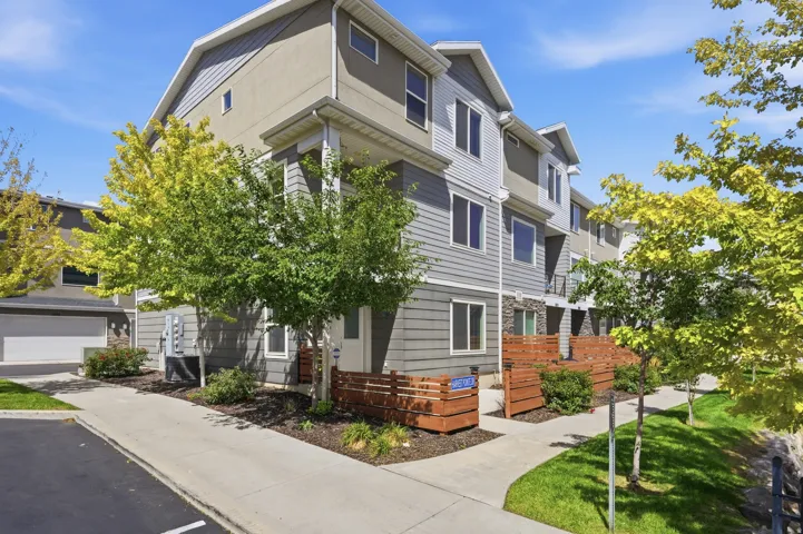 Multi-story exterior with siding and stucco finishes, featuring individual entryways and a paved pathway
