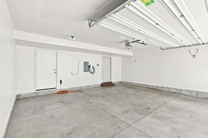 Spacious garage with concrete flooring, overhead lighting, and white walls