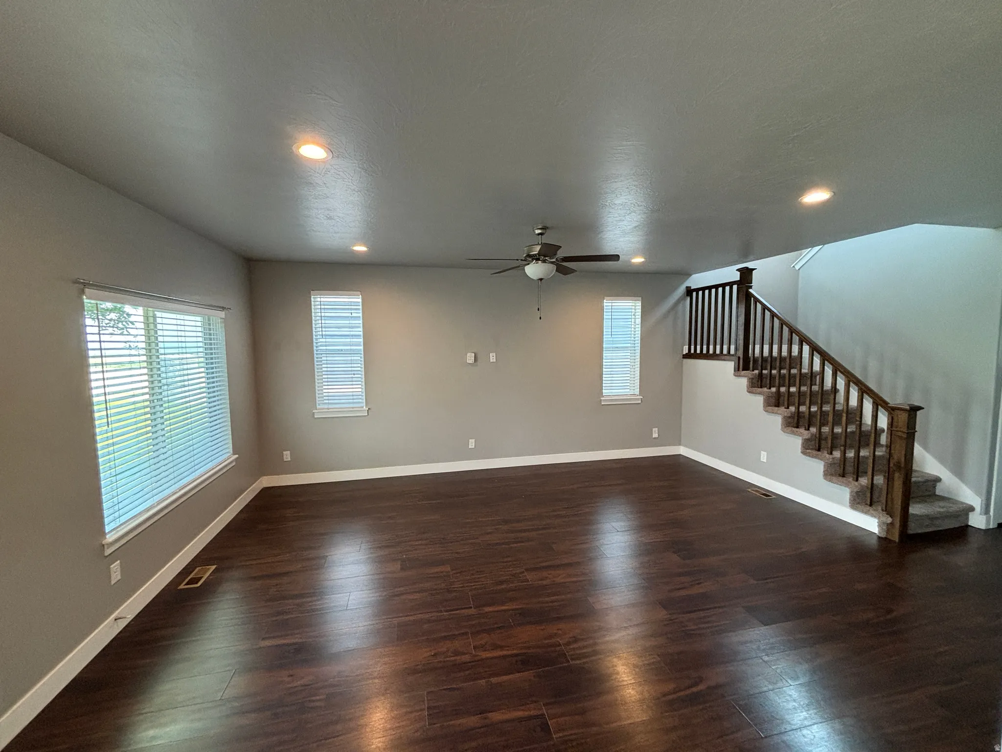 Expansive living area featuring rich wood-finish flooring, recessed lighting, and a ceiling fan