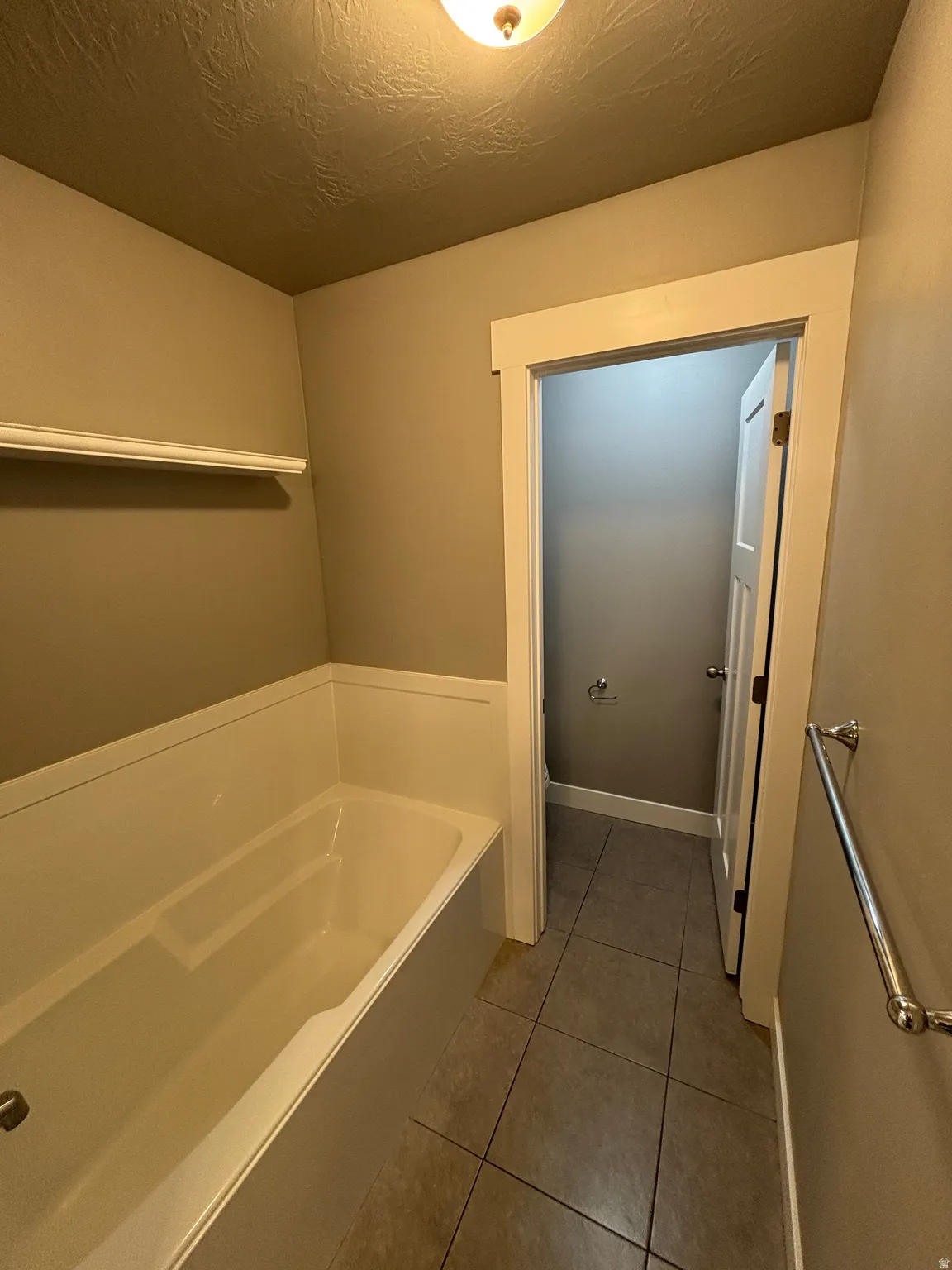 Alcove bathtub with white paneling and a dedicated shower shelf