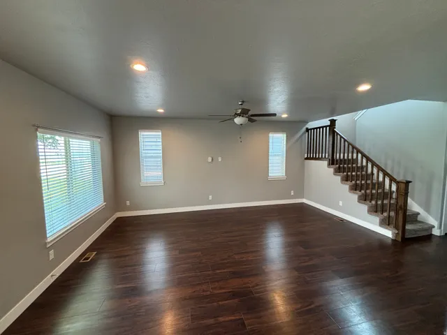 Expansive living area featuring rich wood-finish flooring, recessed lighting, and a ceiling fan