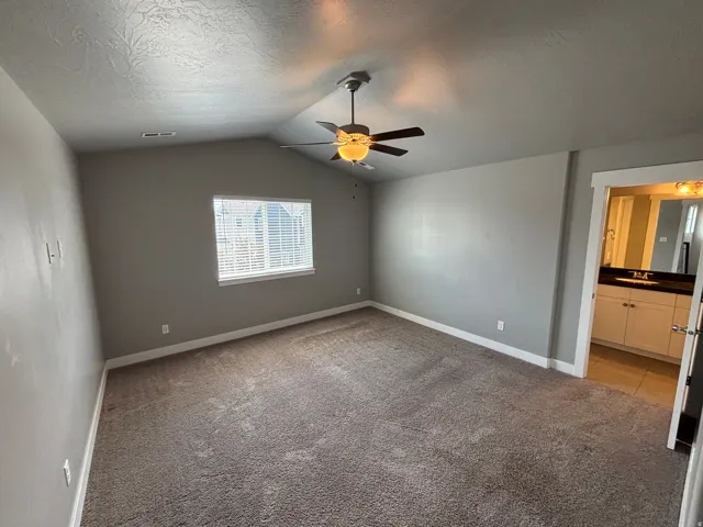 Vaulted ceilings, a window with blinds, a ceiling fan with integrated lighting, and carpeted flooring