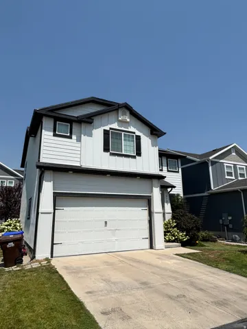 Two-story home with white siding, a black roof, and contrasting black window trim