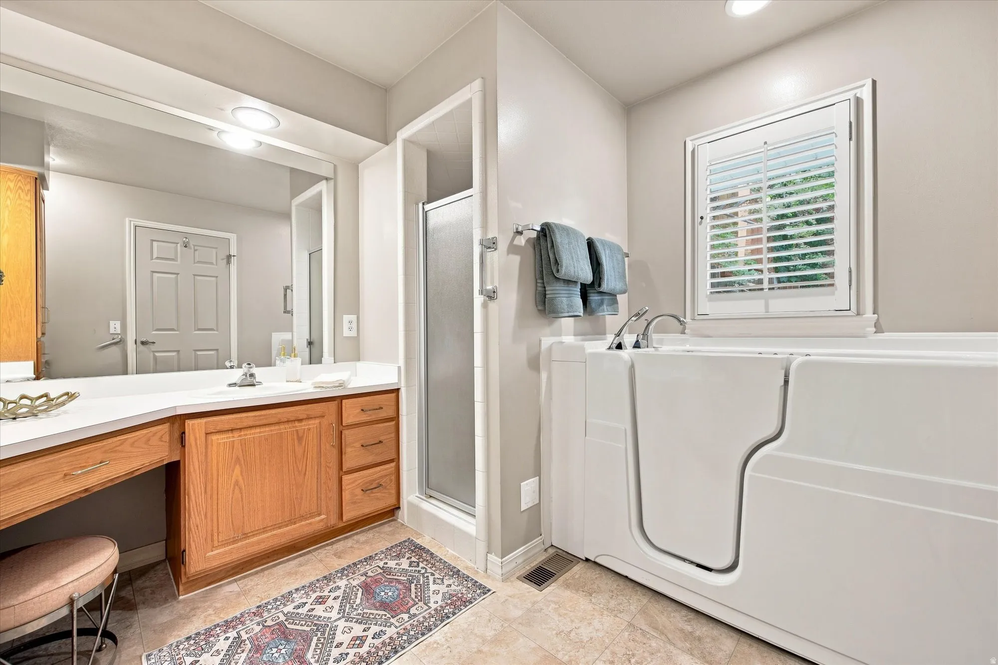 Primary bathroom with shower, double vanity, and accessible walk-in bathtub.