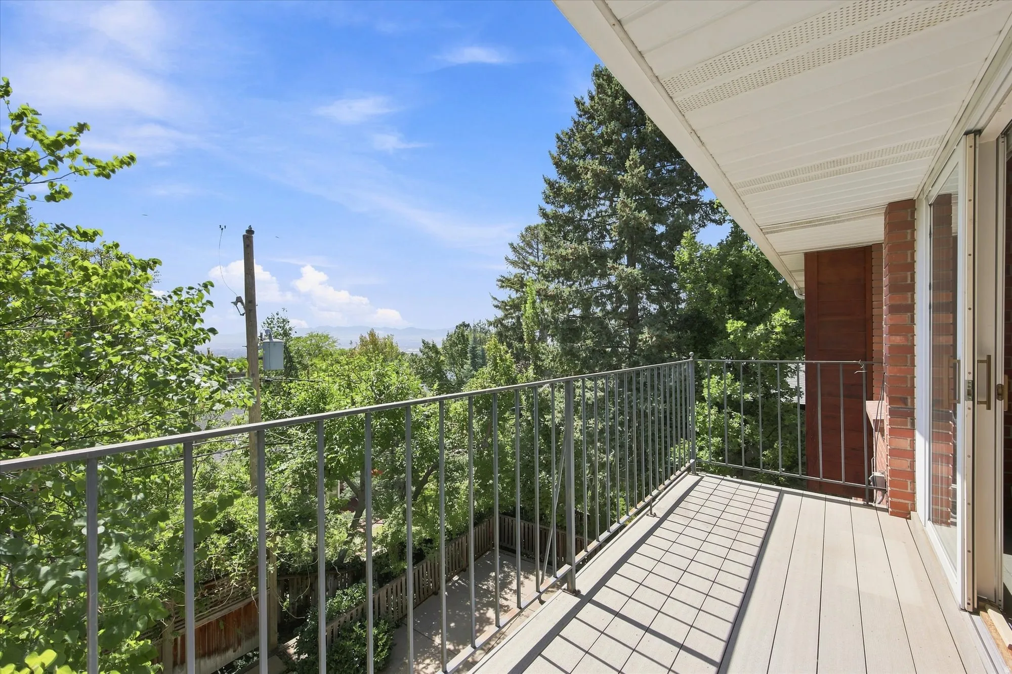 Balcony overlooking the backyard with treetop and city views.