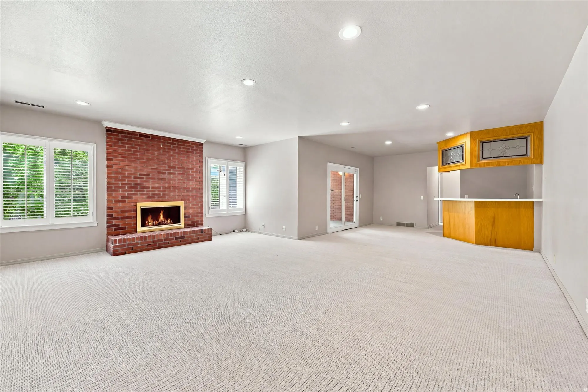 Expansive family room with new carpet, wet bar, gas fireplace and doors to a sunroom and the backyard. Windows are above ground.