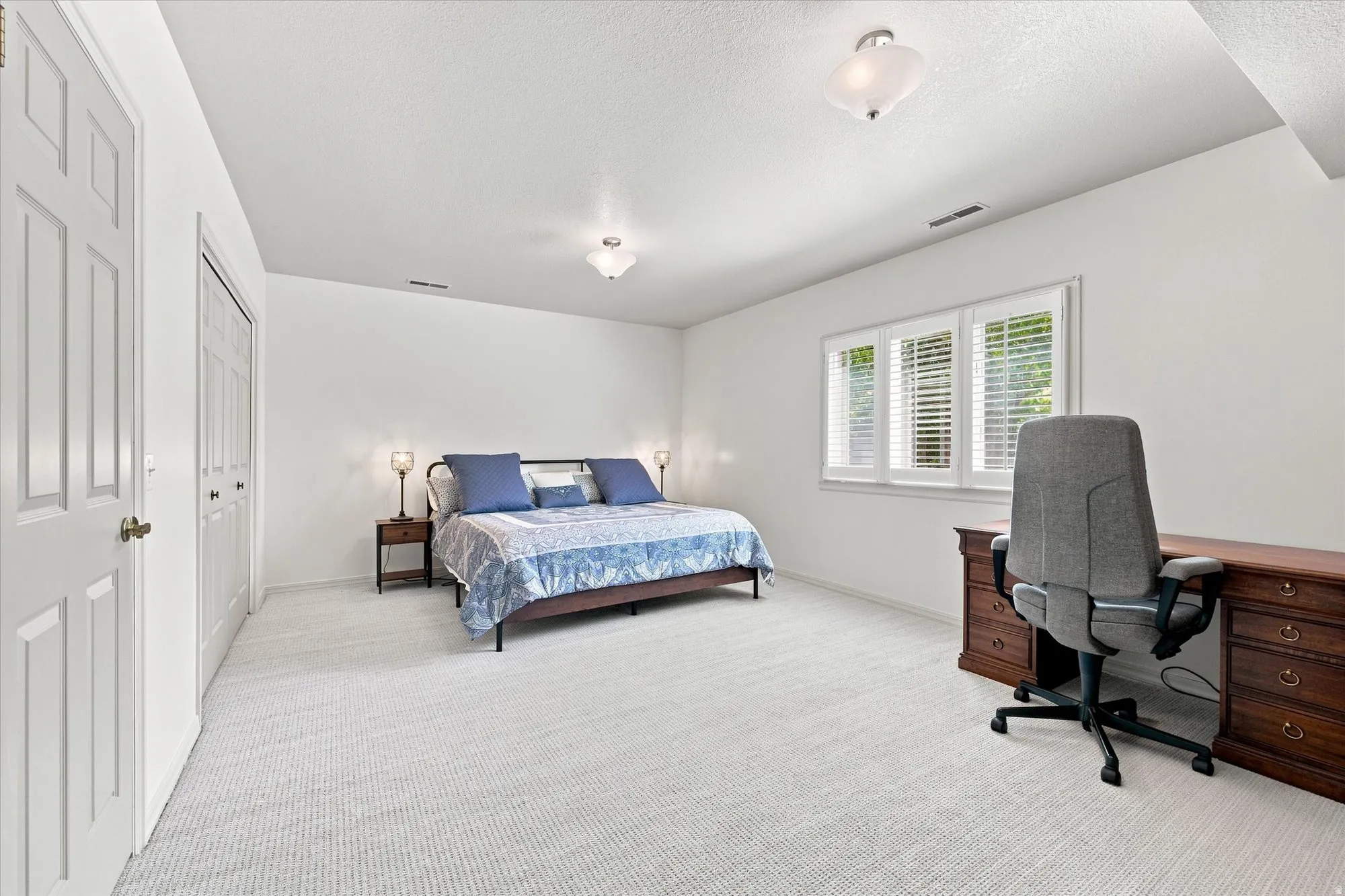 Spacious, light-filled lower-level bedroom with above-grade windows and built-in cabinetry.