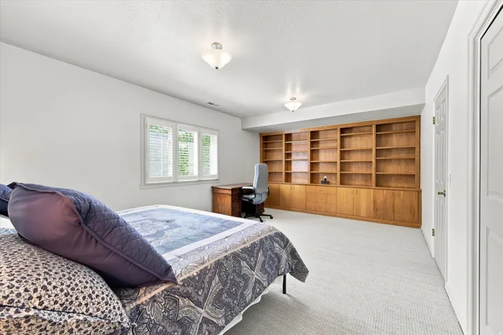 Spacious, light-filled lower-level bedroom with above-grade windows and built-in cabinetry.