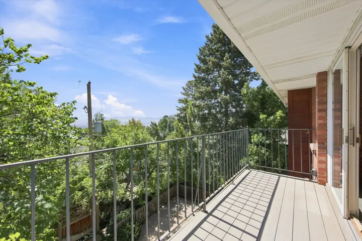 Balcony overlooking the backyard with treetop and city views.