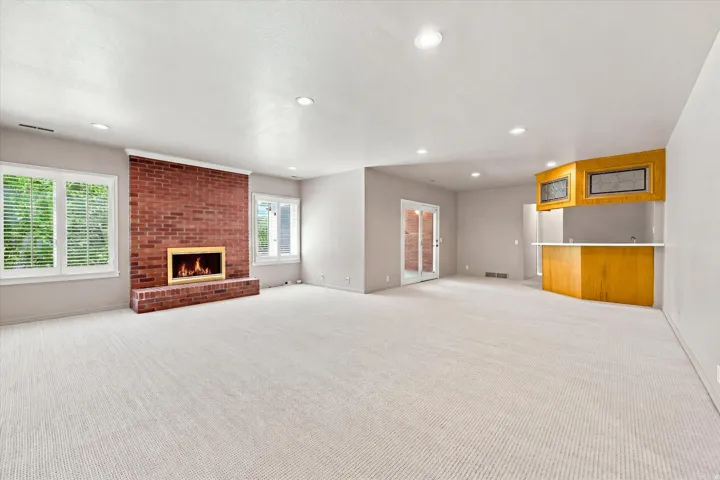 Expansive family room with new carpet, wet bar, gas fireplace and doors to a sunroom and the backyard. Windows are above ground.