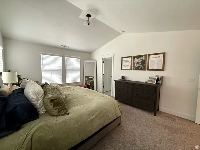 Vaulted ceilings with a semi-flush mount light fixture, carpeting, and double windows with blinds