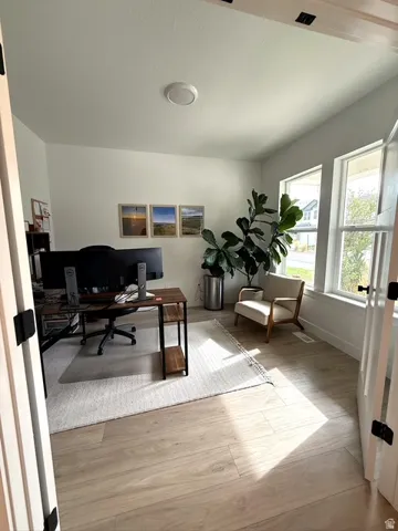 Light-toned wood-finish flooring, white walls, and a prominent window