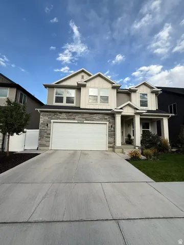 Elegant two-story home featuring a stone and stucco exterior with a pitched roofline and gabled details