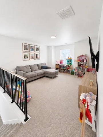 Carpeted open area with recessed lighting, a window, and a black metal railing