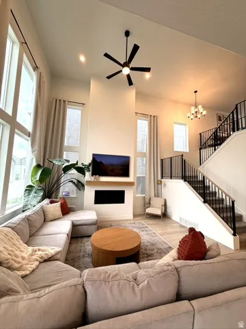 Two-story living area featuring tall windows, recessed lighting, a modern ceiling fan, a built-in fireplace, and wood-finish flooring