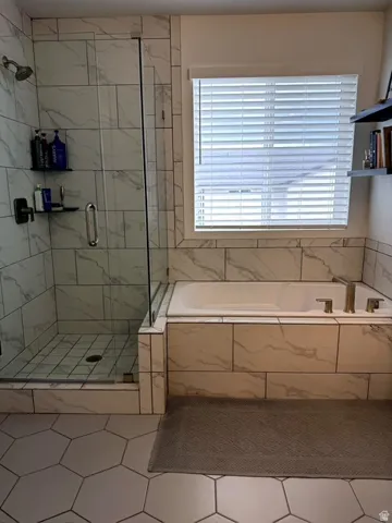 Walk-in shower with clear glass enclosure and tile surround, accompanied by a built-in bathtub with tiled facade