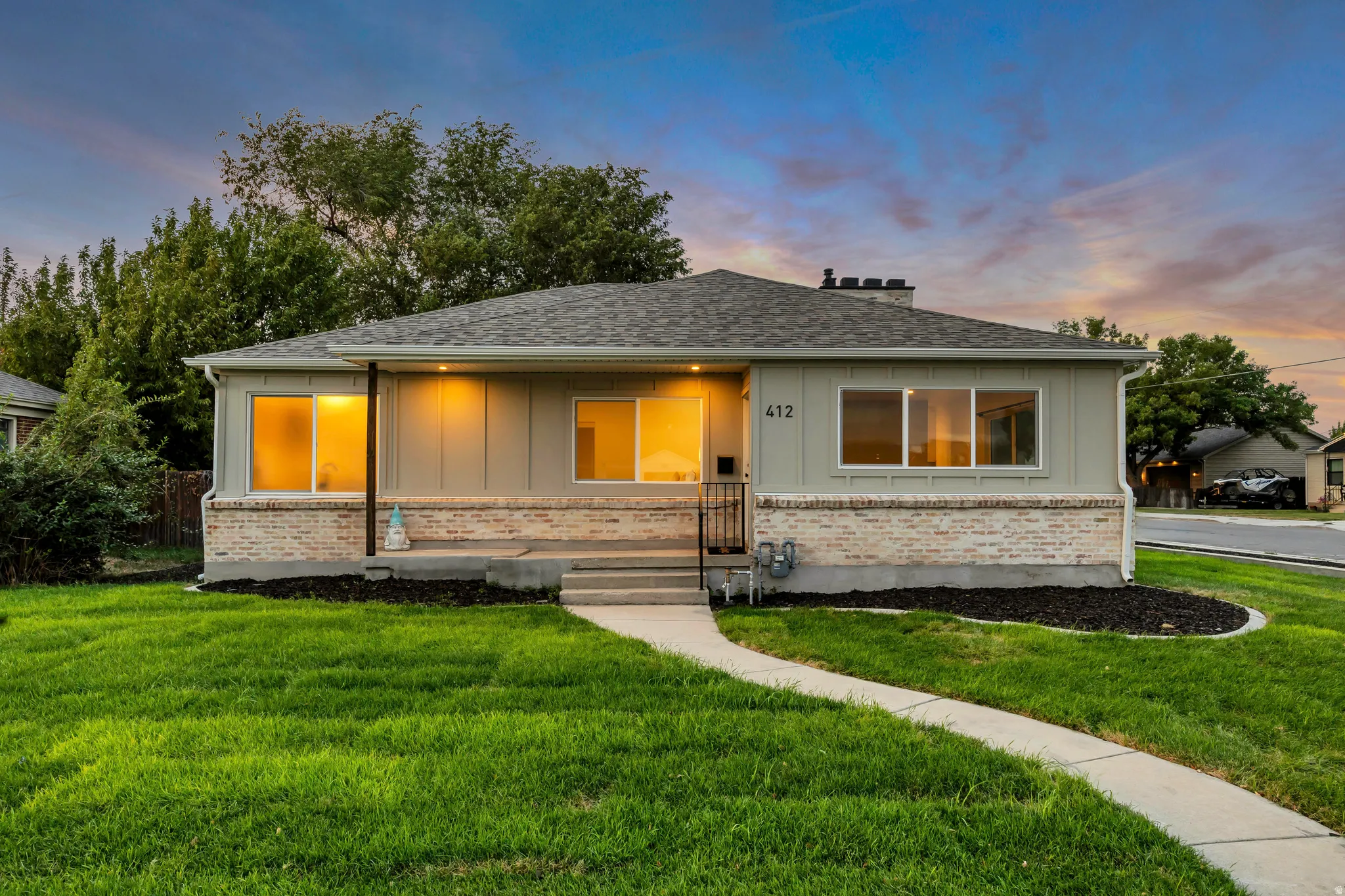 Ranch-style exterior with a brick skirt and light-colored siding