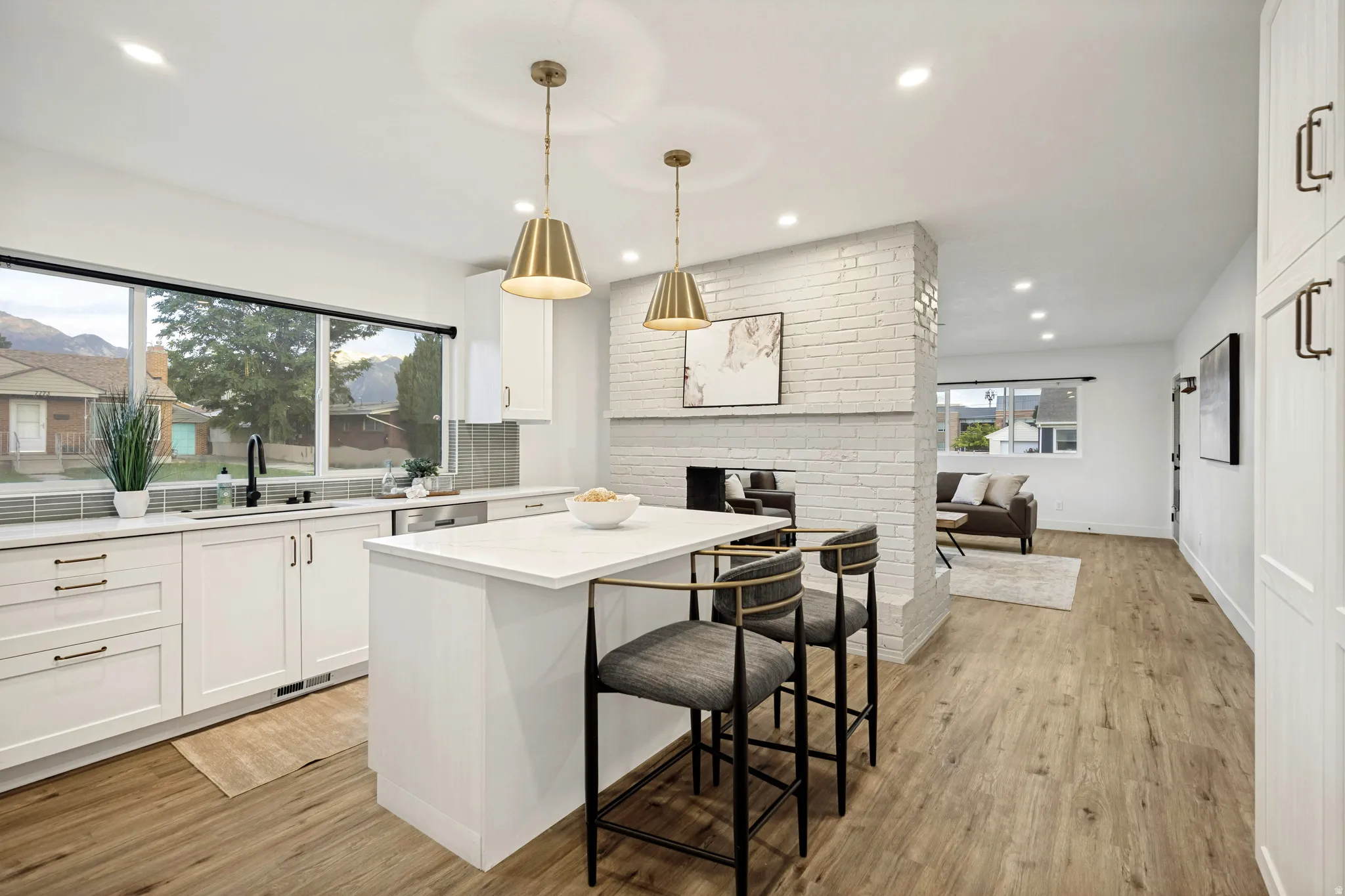 Open-concept kitchen featuring white cabinetry, a central island with countertop seating, and wood-finish flooring