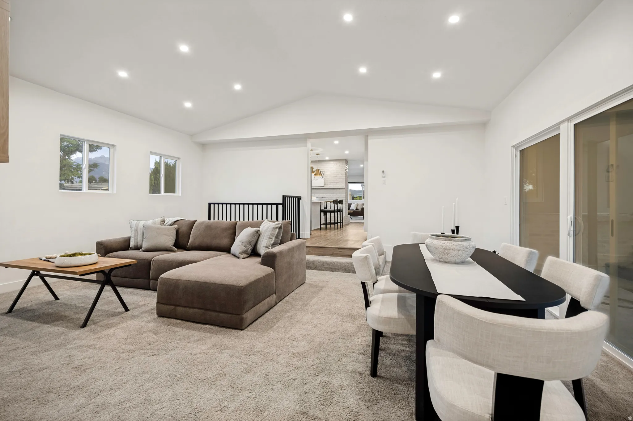 Recessed lighting, large sliding glass door, white walls, and a vaulted ceiling
