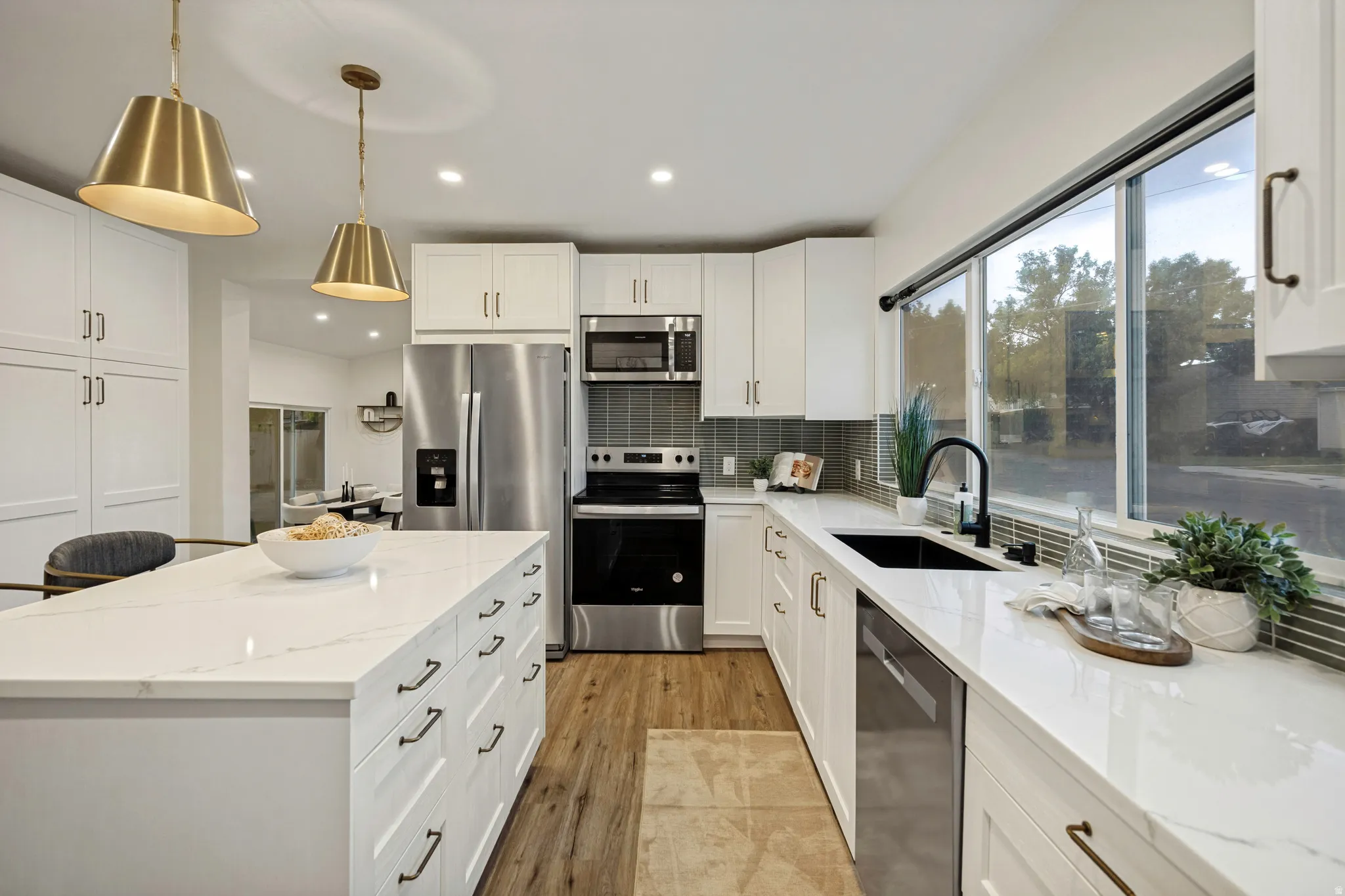 Modern kitchen featuring white cabinetry, a large center island, stainless steel appliances, and wood-finish flooring