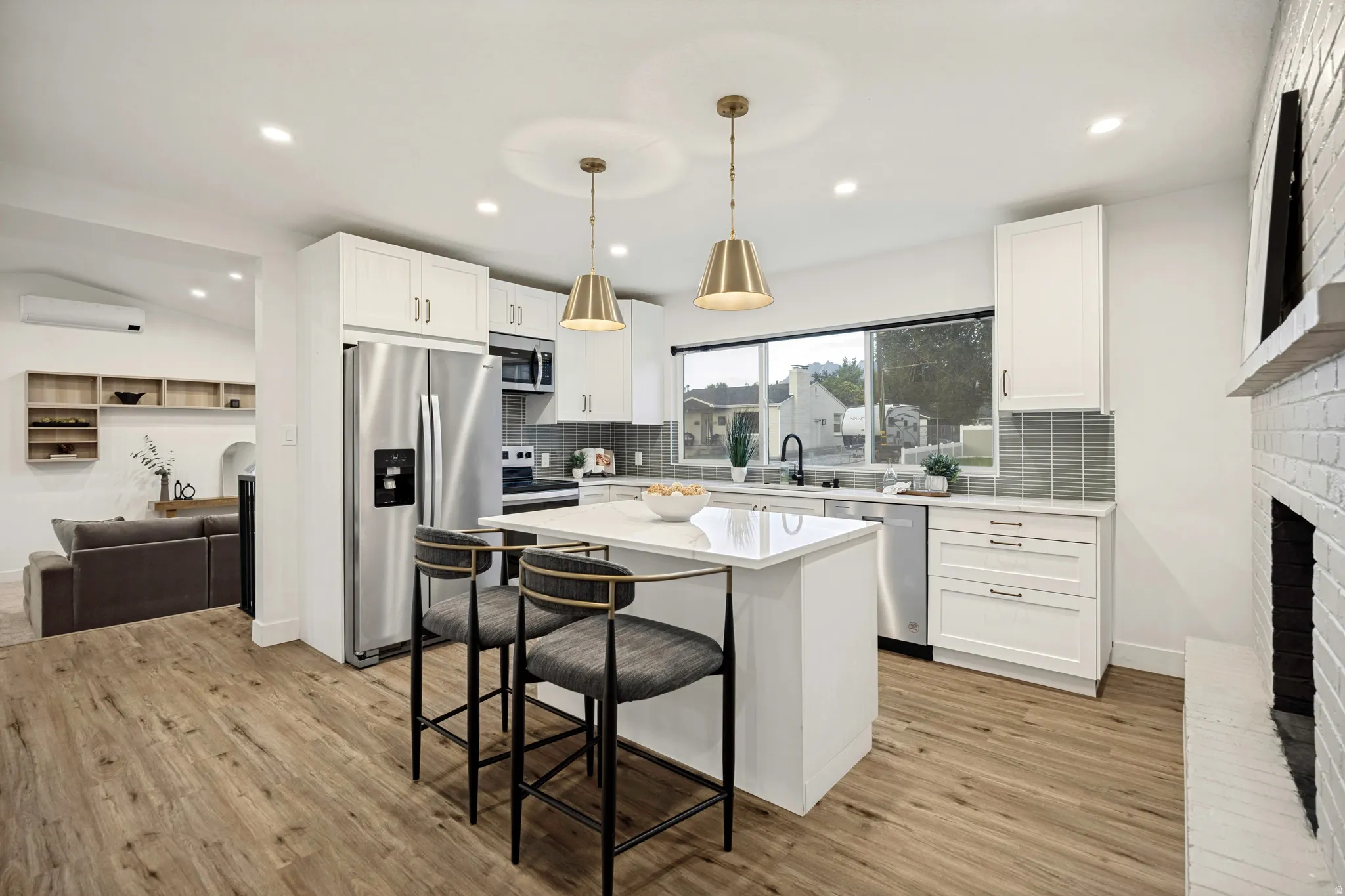 Open-concept kitchen with wood-finish flooring, white cabinetry, stainless steel appliances, and a central island with a countertop